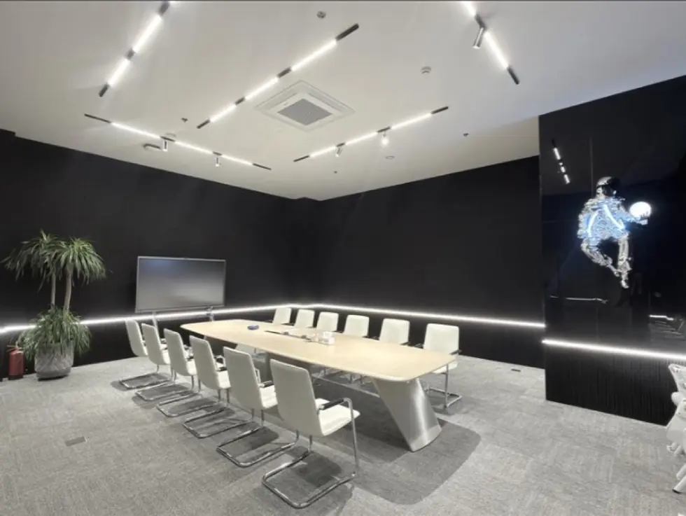 Dark boardroom with linear lighting and an illuminated blue humanoid AI sculpture on the wall